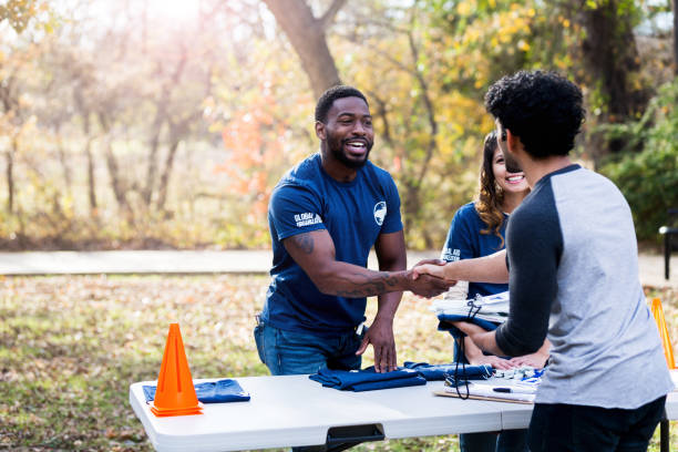 After getting him registered, the mid adult man shakes hands with the unrecognizable volunteer.